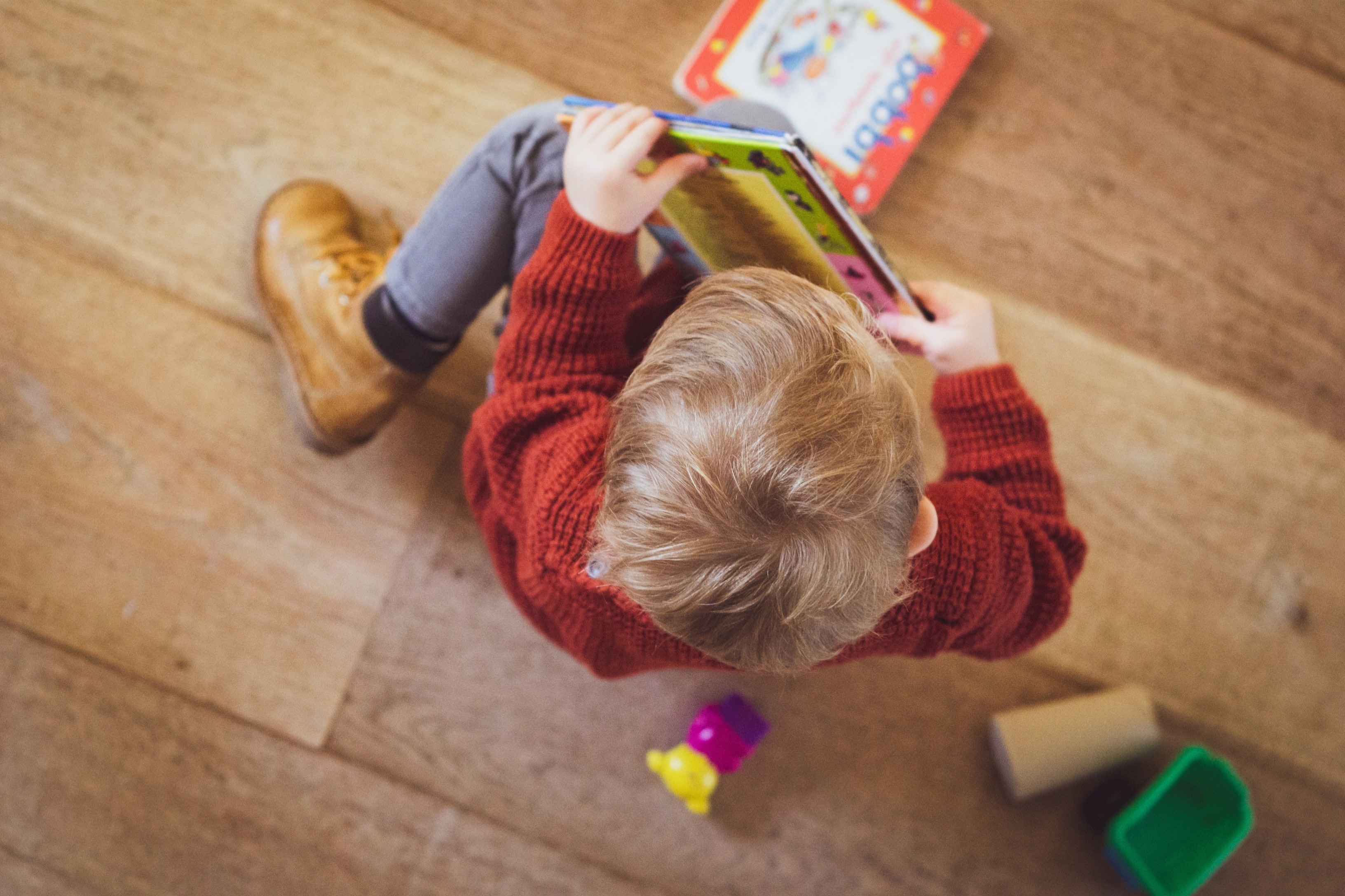 The child sits on the floor and reads.