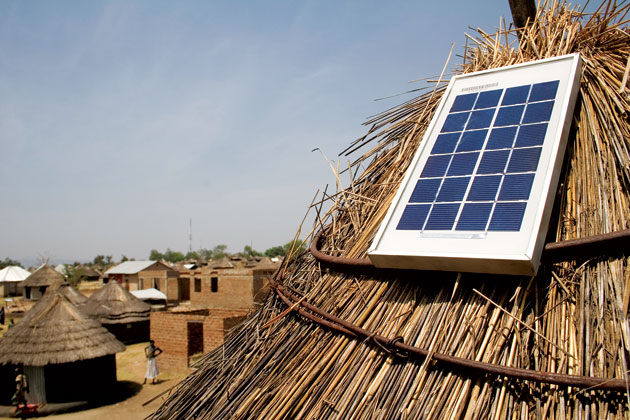 A small solar panel installed on a thatched roof.