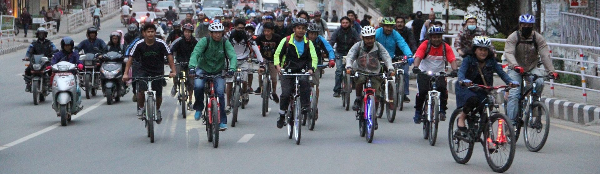 Dozens of cyclists are riding on the road, occupying the entire width of a lane.